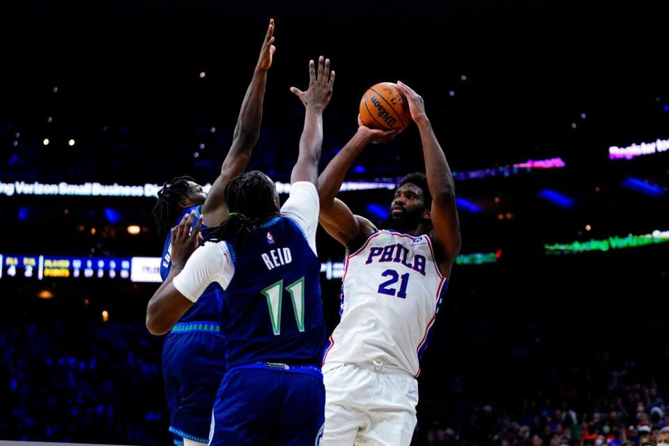 Sixers center Joel Embiid tries to get a shot off over a pair of Timberwolves defenders in the closing seconds of double overtime Saturday. Embiid scored 42 points after missing nine games due to a positive COVID test.