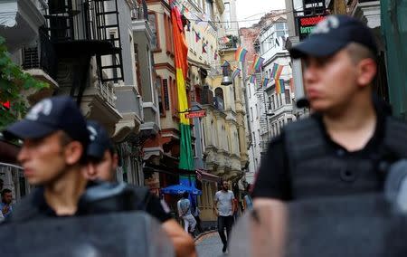 Riot police, with rainbow flags in the background, stand guard at the entrance of a street as LGBT rights activists try to gather for a pride parade, which was banned by the governorship, in Istanbul, Turkey, June 26, 2016. REUTERS/Murad Sezer/Files