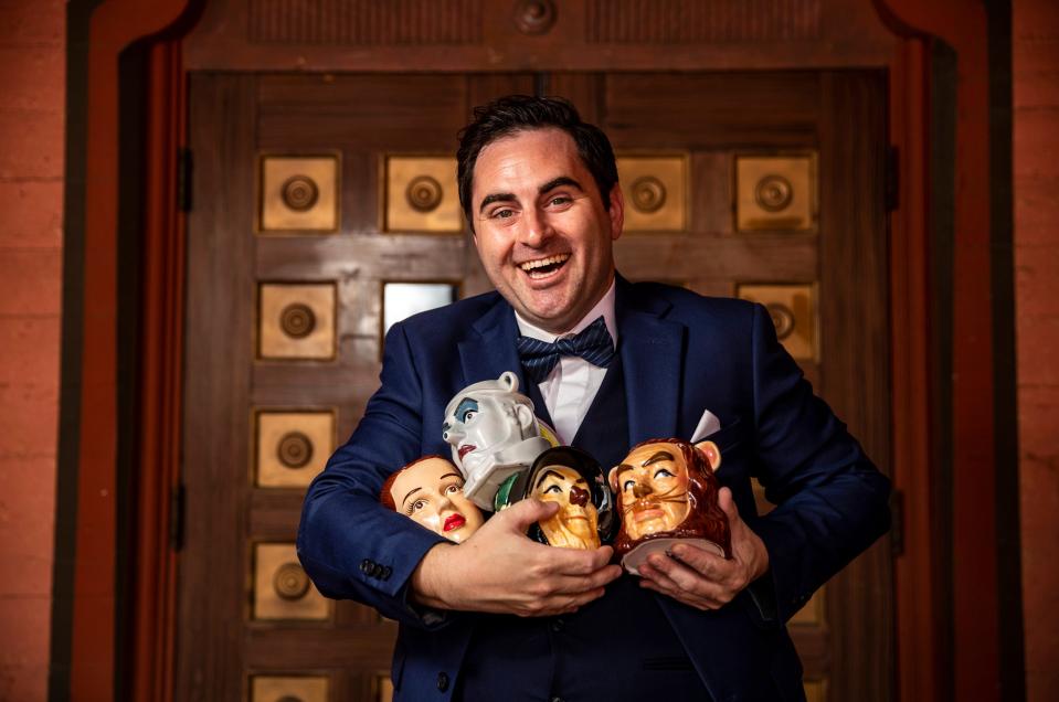 Actor Erik Scott Romney poses for a photo with four Wizard of Oz character mugs at the The Plaza Theatre in Palm Springs, Calif., Saturday, June 17, 2023. Romney plans to gift the mugs to his fellow cast members in his upcoming production of the show. 