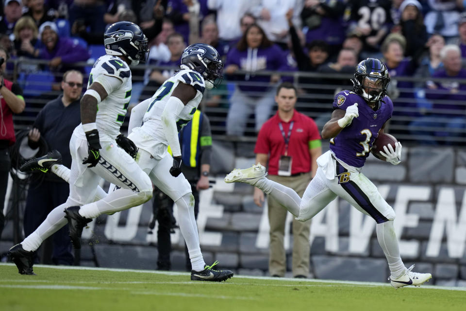 Baltimore Ravens running back Keaton Mitchell, right, runs from Seattle Seahawks defenders during a 40-yard touchdown run in the second half of an NFL football game, Sunday, Nov. 5, 2023, in Baltimore. (AP Photo/Alex Brandon)