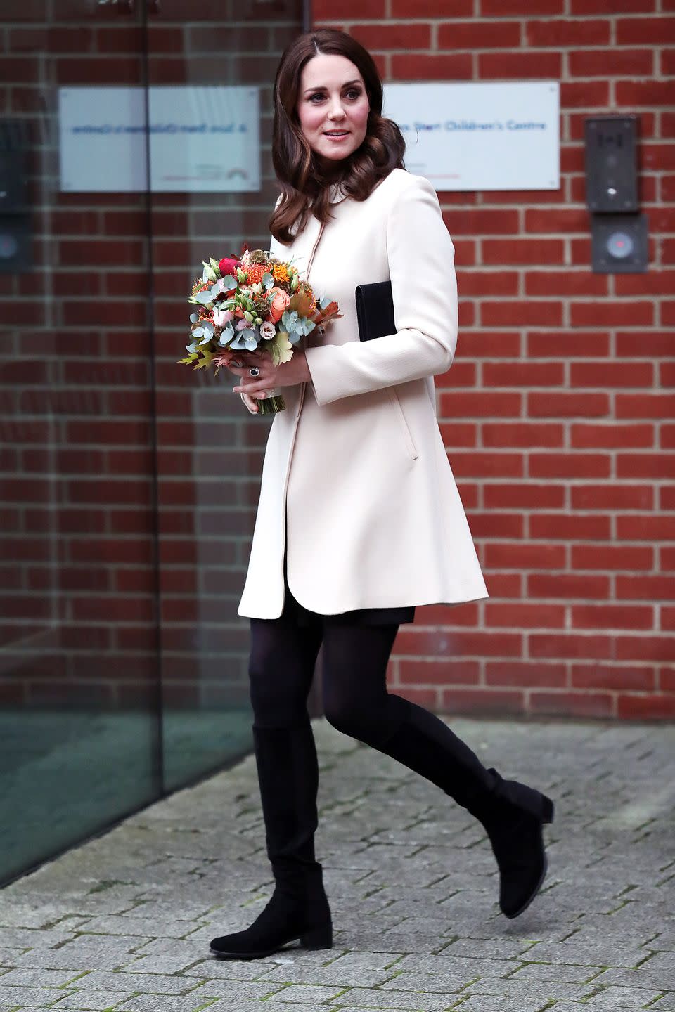 <p>The Duchess wears a pale pink coat, black dress, tights and clutch, and a pair of black suede knee-high boots while leaving the Hornsey Road Children's Centre in London.</p>