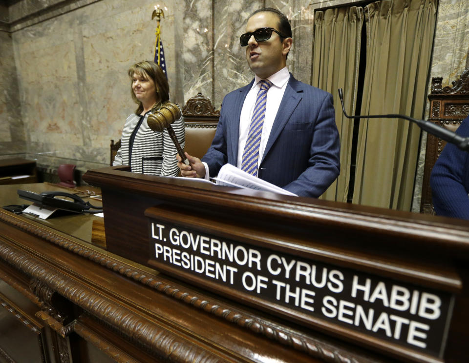 FILE - In this Jan. 5, 2017 file photo, Washington Lt. Gov. Cyrus Habib, right, who is blind, holds the gavel as he stands at the Senate chamber dais next to Senate Counsel Jeannie Gorrell, left, at the Capitol in Olympia, Wash. Habib announced on Thursday, March 19, 2020, that he is not running for re-election and will join the Jesuit order of the Catholic Church as he starts the process of becoming a priest. (AP Photo/Ted S. Warren, File)