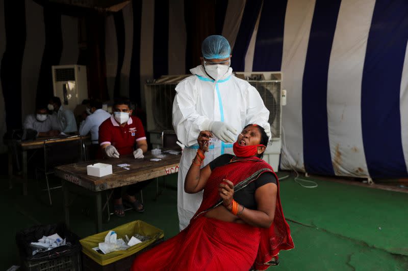 Health worker collects a swab sample from a woman at a vegetable market, in New Delhi