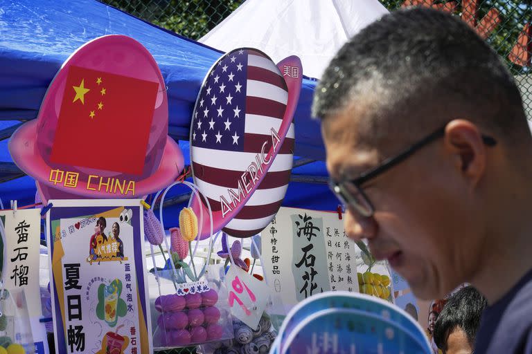 En esta imagen de archivo, un hombre pasa por delante de un puesto de venta de comida y bebida con banderas de China y Estados Unidos, durante una fiesta de primavera en Beijing, el 13 de mayo de 2023. (AP Foto/Andy Wong, archivo)