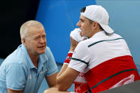 John Isner of the U.S. talks with a trainer before retiring from his third round match against Switzerland's Stan Wawrinka at the Australian Open tennis championship in Melbourne, Australia, Saturday, Jan. 25, 2020. (AP Photo/Andy Wong)