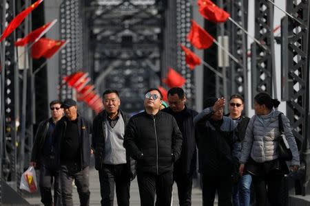 Tourists walk on the Broken Bridge, bombed by the U.S. forces in the Korean War and now a tourist site, over the Yalu River that divides North Korea and China, in Dandong, China's Liaoning province, April 1, 2017. REUTERS/Damir Sagolj/Files