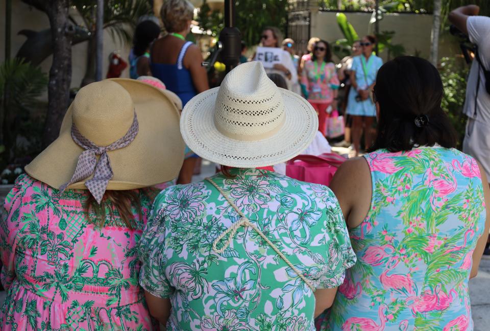 A group of women in Lilly Pulitzer's signature brightly colored prints listen to Leslie Diver of Island Living present a walking tour of Worth Avenue as part of The Pink Retreat on Friday.
