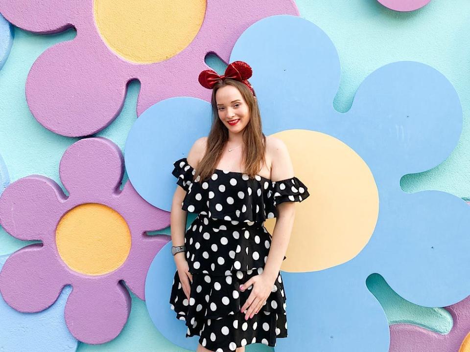 jenna posing for a photo in front of a 70s flower wall at disney's pop century resort 
