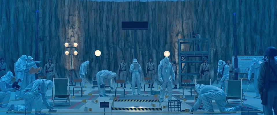 people in white hazard suits deep underground in a crater