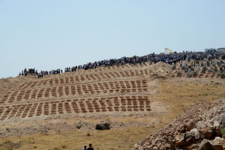 People wait close to empty graves at a cemetery during the funeral for the victims of last night's attack on a wedding party that left 50 dead in Gaziantep in southeastern Turkey near the Syrian border on August 21, 2016