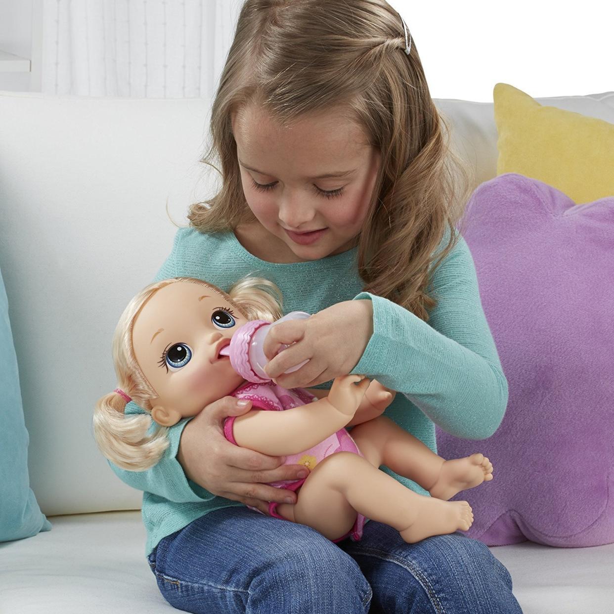 Young girl feeding her Baby Alive Doll in her lap