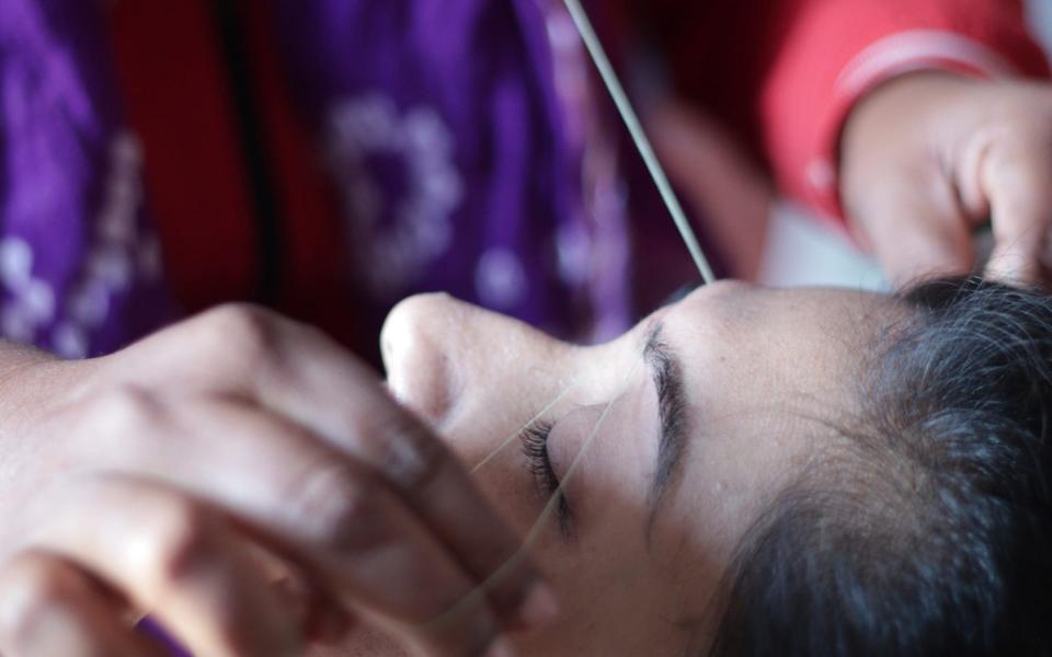 A beautician shapes and plucks a customer's eyebrow - EyeEm