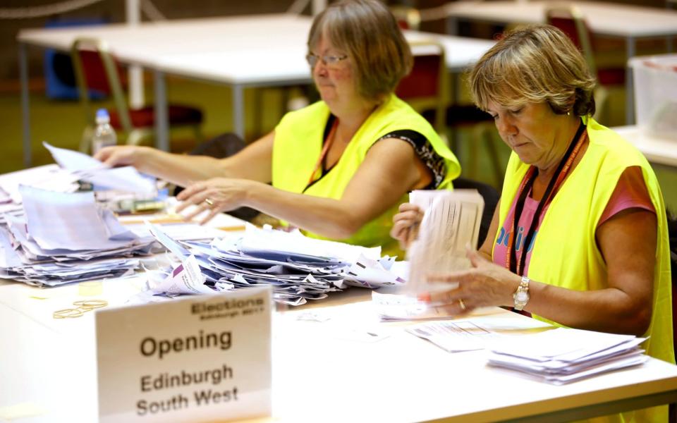 Election staff sort postal votes ahead of the General Election count at Meadowbank Sports Centre in Edinburgh - Credit: PA