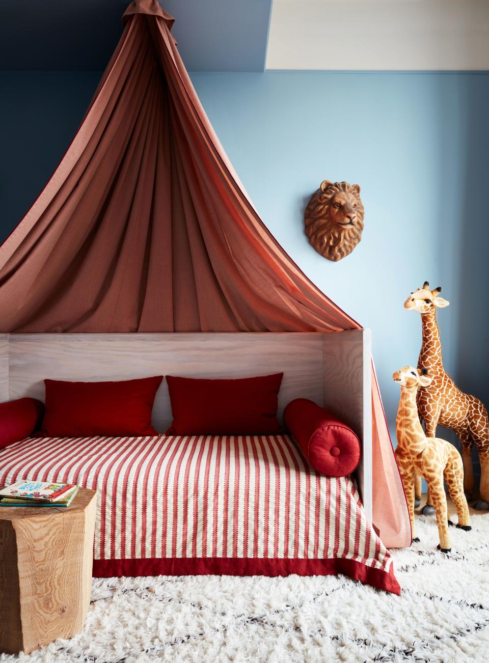 The son’s room, which is painted Lulworth Blue from Farrow & Ball, has a custom canopy bed accented by a decoupage lion’s head from John Derian.