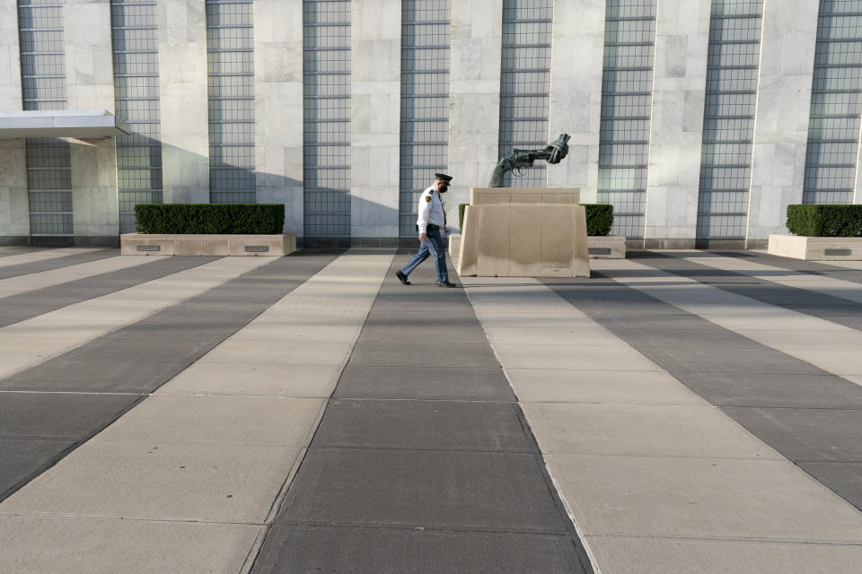 A United Nations Security officer walks past the The Knotted Gun" by Swedish sculpture Carl Fredrik Reutersward during the 75th session of the United Nations General Assembly, Tuesday, Sept. 22, 2020, at U.N. headquarters. This year's annual gathering of world leaders at U.N. headquarters will be almost entirely "virtual." Leaders have been asked to pre-record their speeches, which will be shown in the General Assembly chamber, where each of the 193 U.N. member nations are allowed to have one diplomat present. (AP Photo/Mary Altaffer)