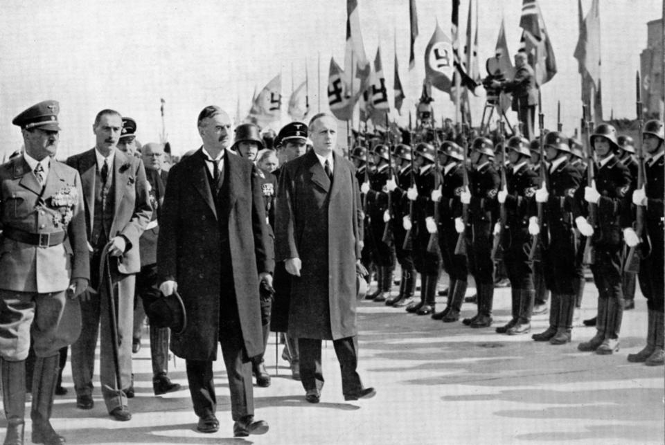 Adolf Hitler and others walk past Nazi soldiers