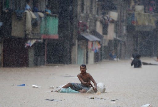 A resident paddles an improvised raft in heavy rain in suburban Manila on August 8, 2012. Philippine authorities appealed Thursday for volunteers to help deliver food, water and other relief goods to two million people affected by deadly floods in and around the Philippine capital