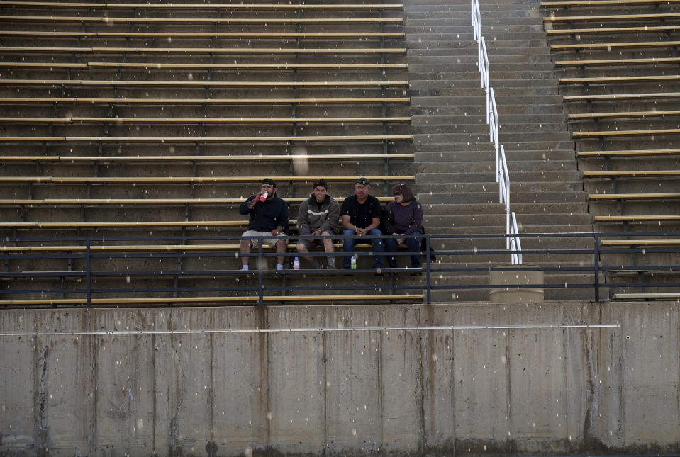 Light rain falls as a group watches drag racing at Bandimere Speedway west of Denver on May 5, 2021. The Colorado State Patrol runs a program called "Take it to the Track" in hopes of luring racers away from public areas to a safer and more controlled environment, even allowing participants to race a trooper driving a patrol car. The program's goals have gained new importance and urgency this year as illegal street racing has increased amid the coronavirus pandemic. (AP Photo/Thomas Peipert)