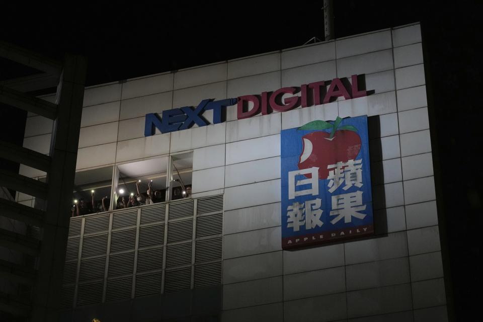 Staff members wave flashlights to their supporters at the Apple Daily headquarters in Hong Kong, Wednesday, June 23, 2021. Hong Kong's pro-democracy Apple Daily newspaper will stop publishing Thursday, following last week's arrest of five editors and executives and the freezing of $2.3 million in assets under the city's one-year-old national security law. (AP Photo/Kin Cheung)