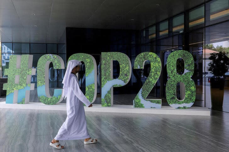 Imagen de archivo de una persona pasando frente a un cartel del COP28 durante un encuentro climático en Abu Dabi, EAU.