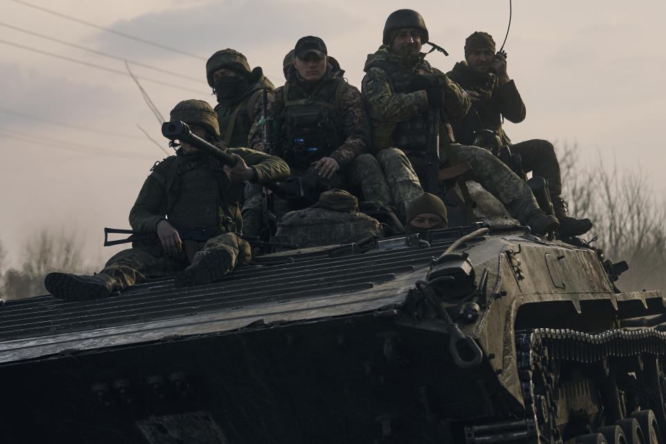 Ukrainian soldiers ride atop an APC on the frontline in Bakhmut, Donetsk region, Ukraine, Wednesday, March 22, 2023. (AP Photo/Libkos)