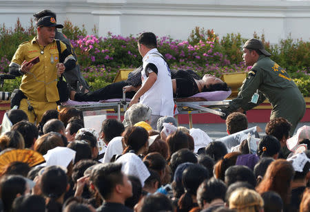 A mourner is attended to after passing out while waiting for the motorcade carrying the body of King Bhumibol Adulyadej outside the Grand Palace in Bangkok, Thailand October 14, 2016. REUTERS/Edgar Su