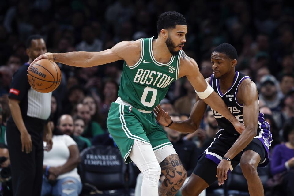 Boston Celtics' Jayson Tatum (0) keeps the ball away from Sacramento Kings' De'Aaron Fox (5) during the first half of an NBA basketball game Friday, April 5, 2024, in Boston. (AP Photo/Michael Dwyer)