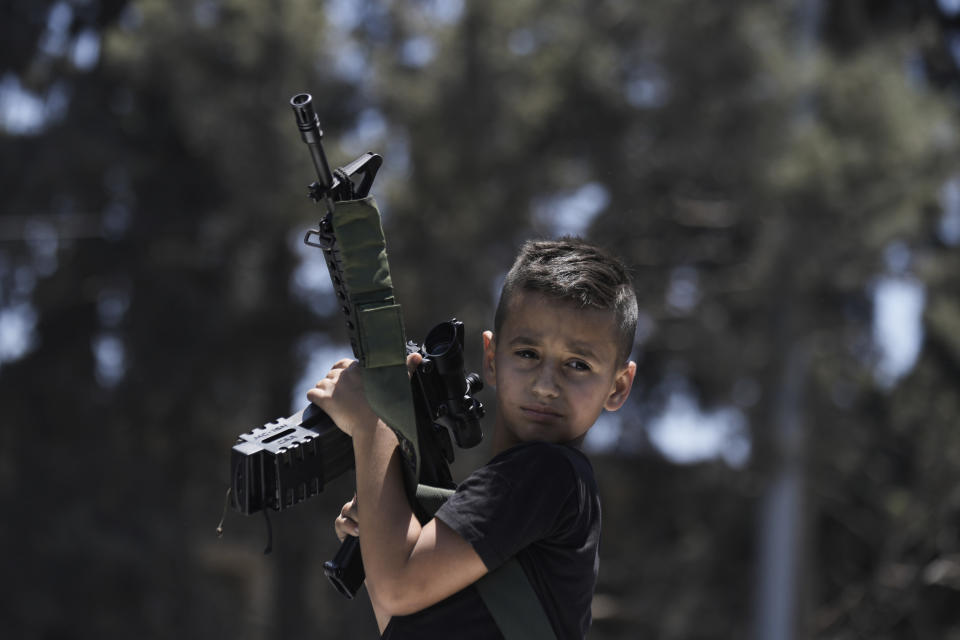 A Palestinian kid holds an M-16 rifle during the funeral of those who were killed during an Israeli army operation, in the Jenin refugee camp, West Bank, Wednesday, July 5, 2023. The Israeli military says it withdrew its troops from the camp on Wednesday, ending an intense two-day operation that killed at least 13 Palestinians, drove thousands of people from their homes and left a wide swath of damage in its wake. One Israeli soldier was also killed. (AP Photo/Majdi Mohammed)