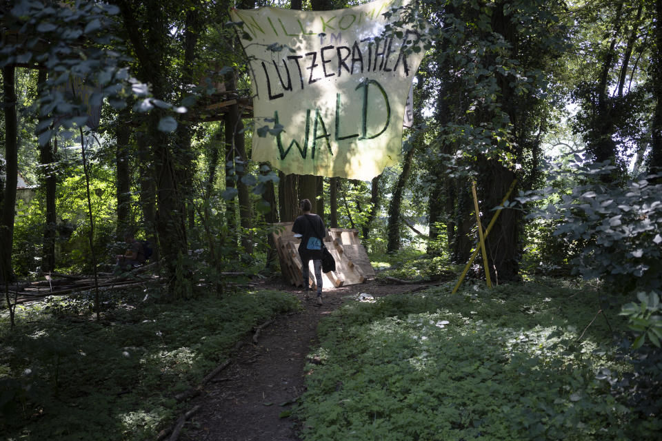 A banner reading '"Welcome in Luetzerath forest" hangs in a forest in Luetzerath, Germany, where activists camp to try and stop the construction of a coal mine, Tuesday, July 20, 2021. The village is located just a few hundred meters from a vast pit where German utility giant RWE is extracting lignite coal to burn in nearby power plants.(AP Photo/Bram Janssen)