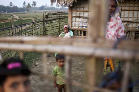 Internally displaced Rohingya women and children look from behind the fence of their temporary home at Thae Chaung IDP camp on the outskirts of Sittwe, February 15, 2015. REUTERS/Minzayar