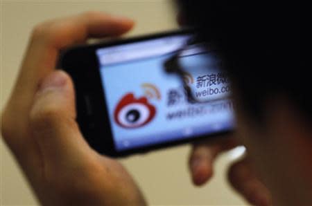 A man holds an iPhone as he visits Sina's Weibo microblogging site in Shanghai in this May 29, 2012 file photo. REUTERS/Carlos Barria/Files