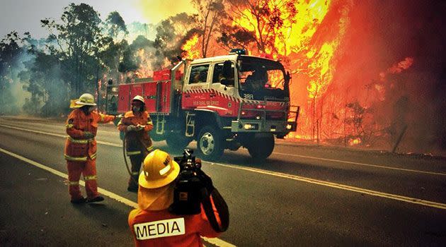 Firefighters and media crew at the site of a grass fire in northwest Sydney. Photo: AAP