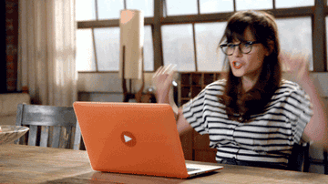 Woman sitting down celebrating by her laptop.