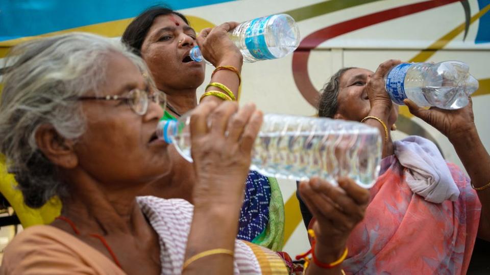 Mujeres en India beben agua durante una ola de calor.