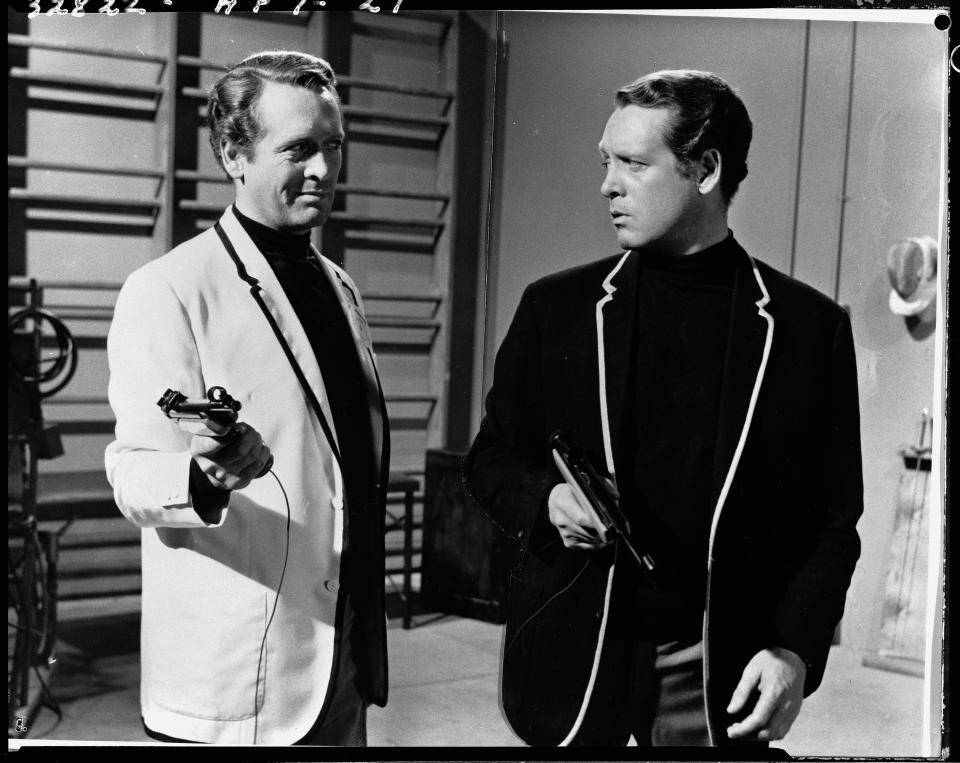American-born Irish actor Patrick McGoohan in character as both Number Six (right) and his doppelganger Charles Curtis, Number 12, as they hold sporting pistols and look at each other in a gymnasium during the episode 'Schizoid Man' of the cryptic adventure series 'The Prisoner,' United Kingdom, 1968. (Photo by CBS Photo Archive/Getty Images)