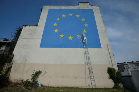 An artwork attributed to street artist Banksy, depicting a workman chipping away at one of the 12 stars on the flag of the European Union, is seen on a wall in the ferry port of Dover, Britain May 7, 2017. REUTERS/Hannah McKay