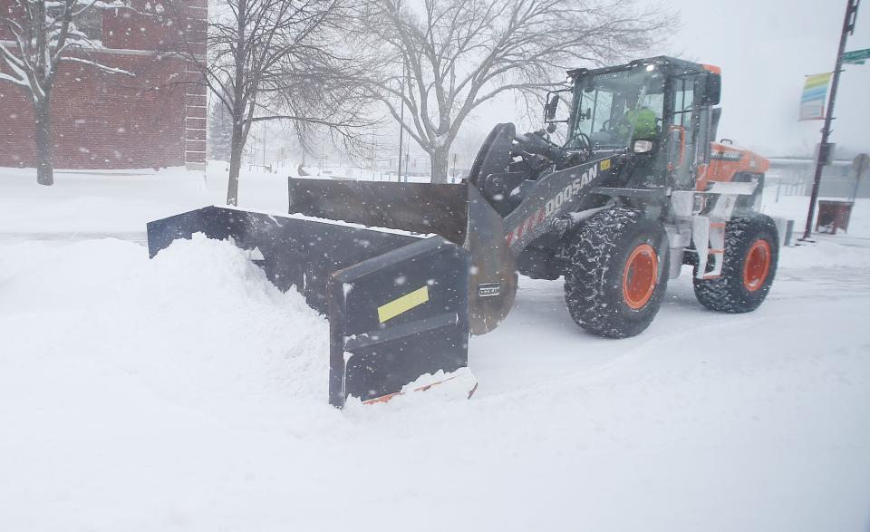 A city worker cleans snow from downtown parking lot with a bulldozer during a winter storm in Ames, Iowa, on Friday, Jan. 12, 2024.