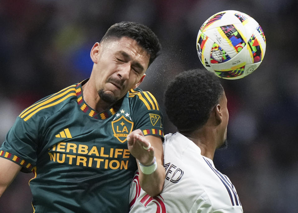 LA Galaxy's Mark Delgado, left, and Vancouver Whitecaps' Ali Ahmed vie for the ball during the first half of an MLS soccer match Saturday, April 13, 2024, in Vancouver, British Columbia. (Darryl Dyck/The Canadian Press via AP)