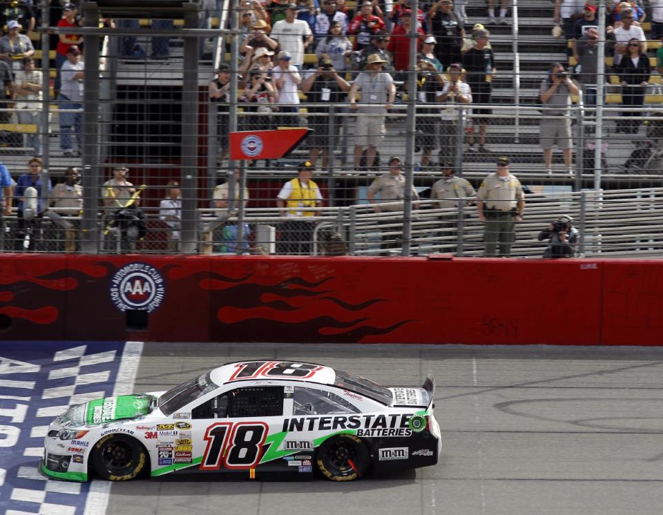 Kyle Busch (18) crosses the finish line to win the NASCAR Sprint Series auto race in Fontana, Calif., Sunday, March 23, 2014. (AP Photo/Alex Gallardo)