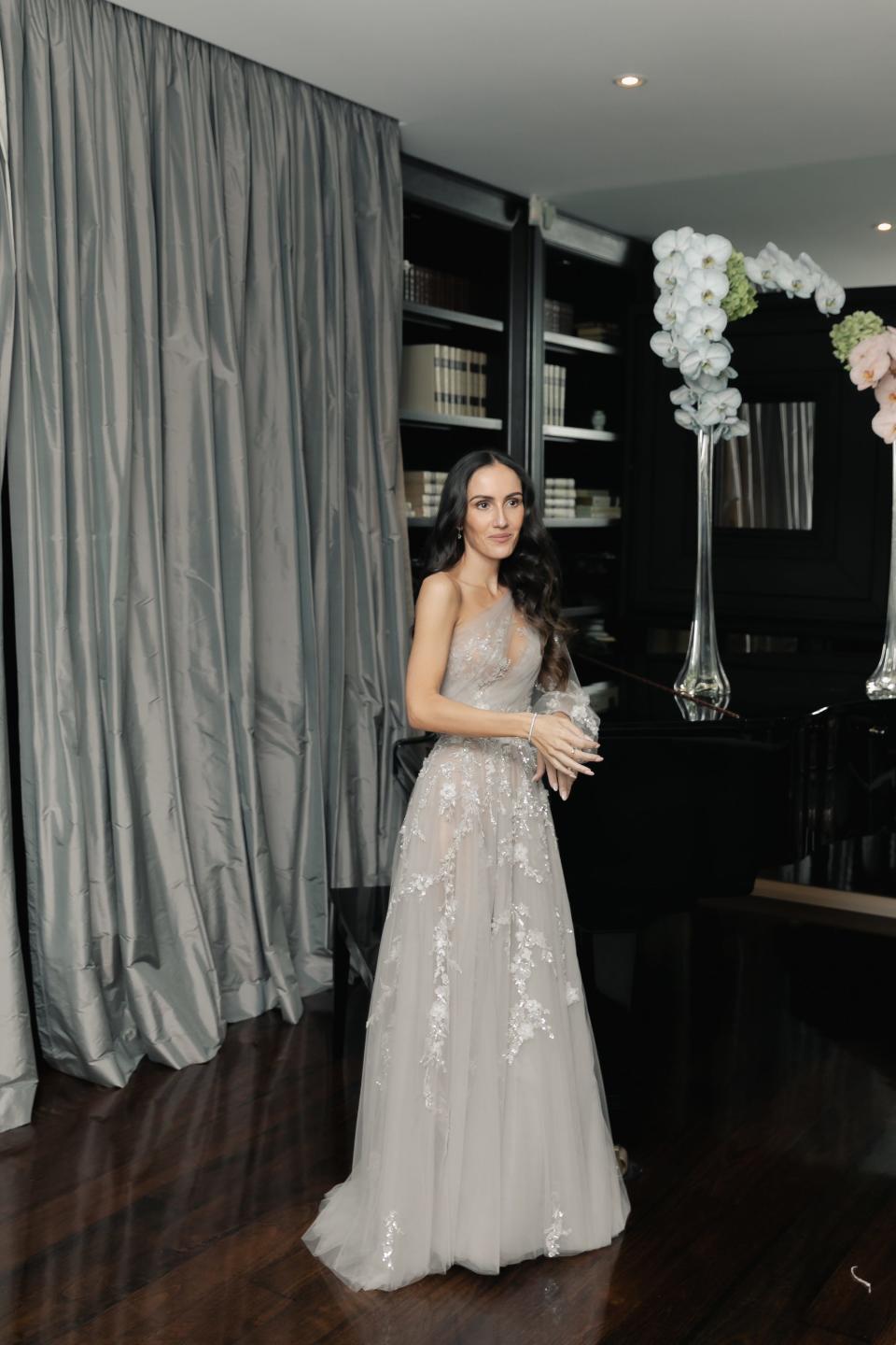 A bride stands in a grey dress on her wedding day.