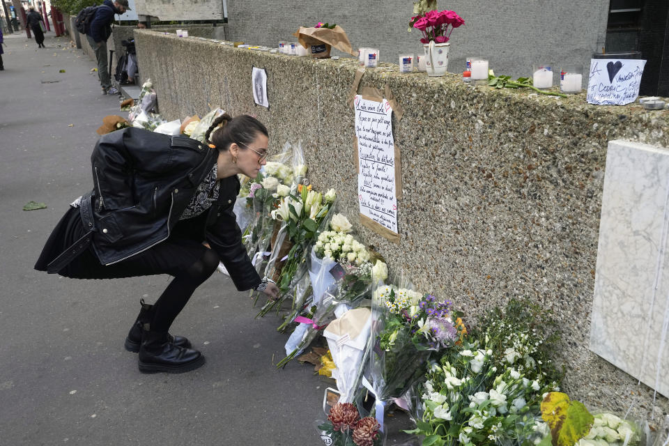 A woman lays flowers outside the building where the body of 12-year-old schoolgirl was discovered in a trunk, in Paris, Wednesday, Oct. 19, 2022. France has been "profoundly shaken" by the murder of a 12-year-old schoolgirl, whose body was found in a plastic box, dumped in a courtyard of a building in northeastern Paris, the government spokesman Olivier Veran said on Wednesday. (AP Photo/Michel Euler)