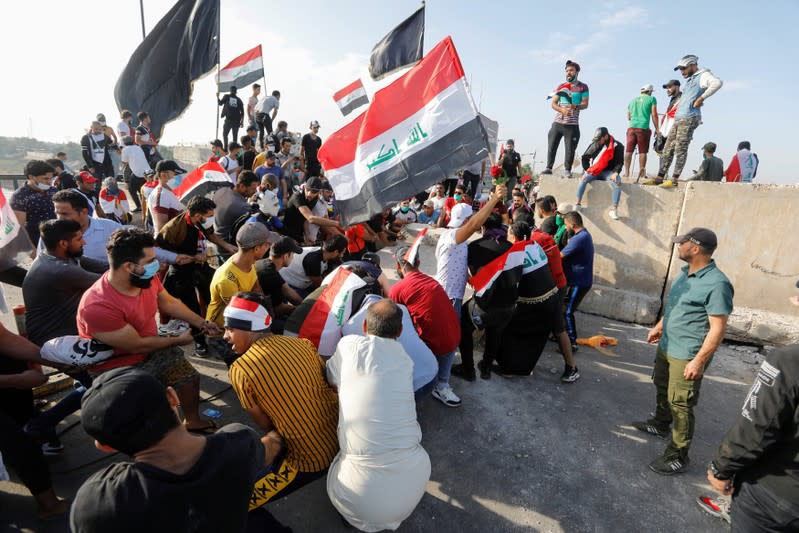 Protesters push down concrete walls during a protest over corruption, lack of jobs, and poor services, in Baghdad