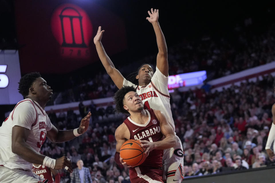 Alabama guard Mark Sears (1) goes in for a shot as Georgia's Silas Demary Jr. (4) and Russel Tchewa (54) defend in the first half of an NCAA college basketball game Wednesday, Jan. 31, 2024, in Athens, Ga. (AP Photo/John Bazemore)