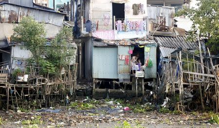 A woman holds a water bucket at a slum house by the Mekong river in Can Tho city, Vietnam April 2, 2016. REUTERS/Kham