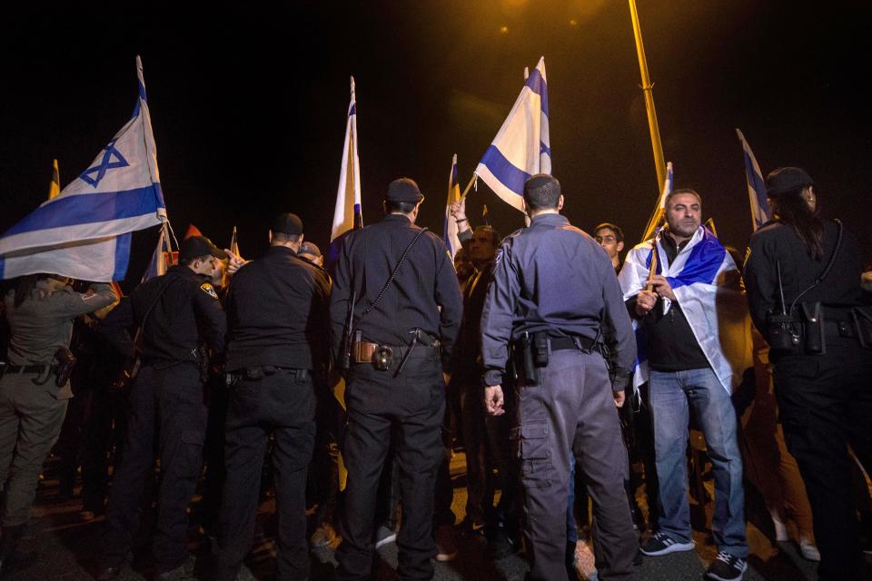 Israeli protesters hold flags during a demonstration against the cease-fire between Israel and Gaza's Hamas in the southern Israeli city of Ashkelon, Wednesday, Nov. 14, 2018. Israel's defense minister on Wednesday abruptly resigned to protest a new cease-fire with Hamas militants in Gaza, throwing the government into turmoil and pushing the country toward an early election. (AP Photo/Tsafrir Abayov)