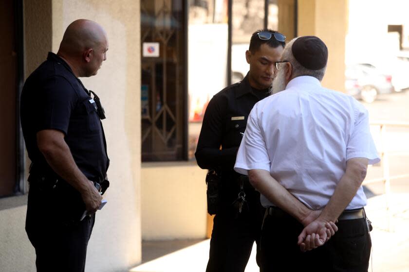 LOS ANGELES, CA - NOVEMBER 1, 2023 - Los Angeles police officers take a statement from Rabbi Yosef Mishulovin, owner of Chabad Atara's Judaica, about grafitti placed on the sidewalk in front of the store in the Fairfax District in Los Angeles on November 1, 2023. The graffiti said, "Free Gaza." (Genaro Molina / Los Angeles Times)