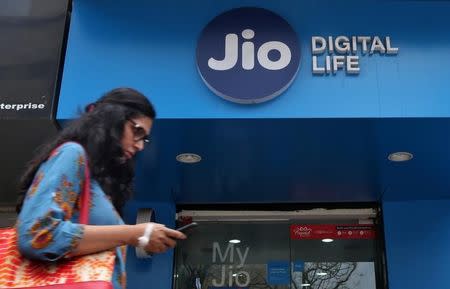 A woman checks her mobile phone as she walks past a mobile store of Reliance Industries' Jio telecoms unit, in Mumbai, India, July 11, 2017. REUTERS/Shailesh Andrade