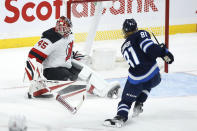 A shot by Winnipeg Jets' Kyle Connor is stopped by New Jersey Devils goaltender Jonathan Bernier (45) during the first period of an NHL hockey game Friday, Dec. 3, 2021, in Winnipeg, Manitoba. (John Woods/The Canadian Press via AP)