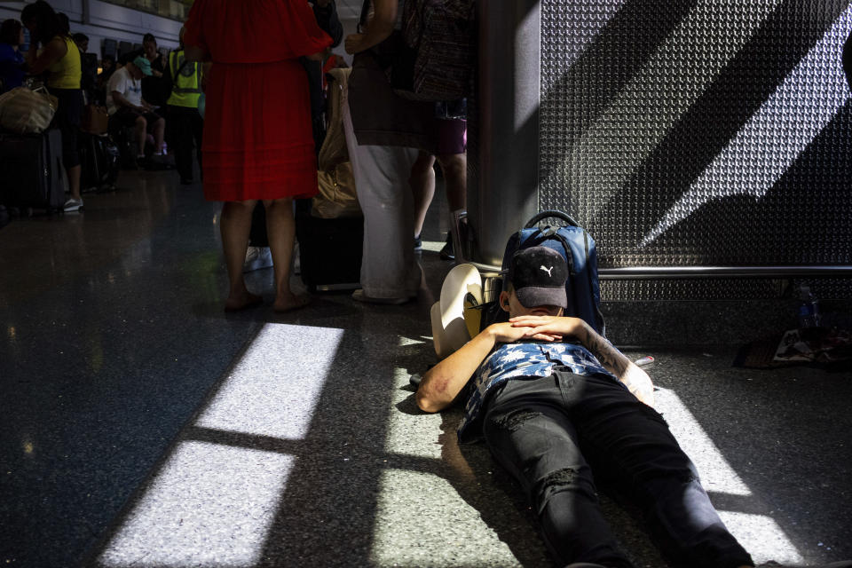 A passenger takes a nap inside a terminal at Harry Reid International Airport on Friday, July 19, 2024, after a faulty CrowdStrike update caused a major internet outage for computers running Microsoft Windows. (AP Photo/Ty ONeil)