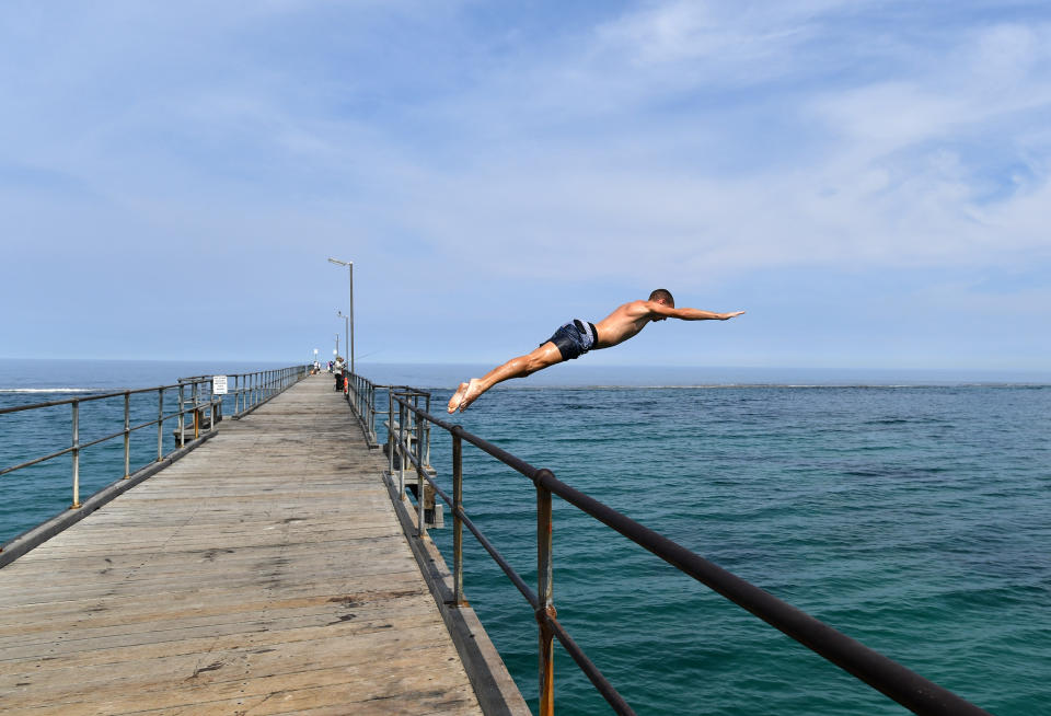 A swimmer jumps from the Port Noarlunga Jetty in Adelaide.